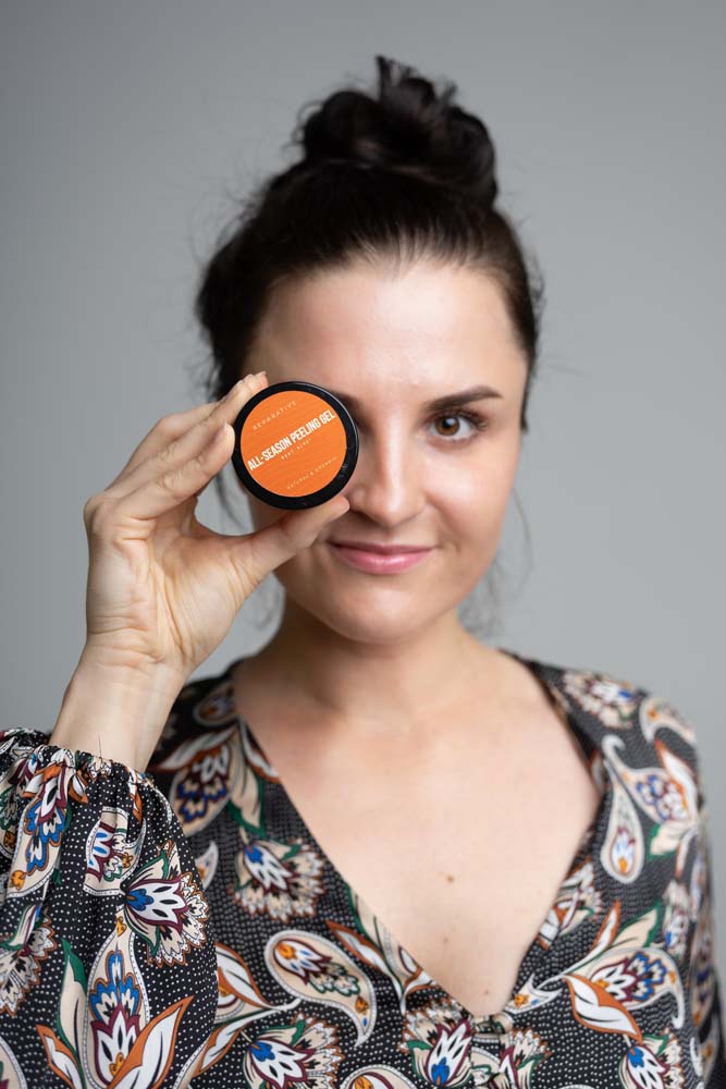 Women in flower dress holding reparative skincare product